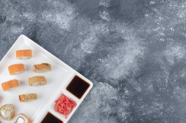 Beyaz tabak çeşitli lezzetli suşi mermer zemin üzerinde rulo