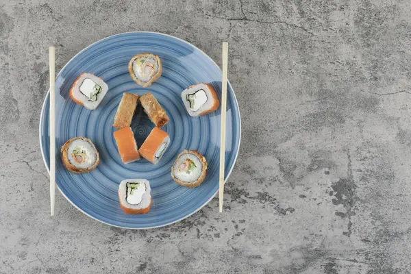 Blå platta med läckra sushi rullar på marmor bakgrund — Stockfoto