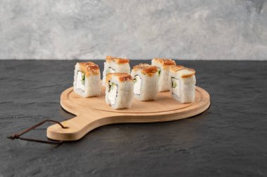 Lezzetli ejderha suşisi ahşap tahtada yılan balığı ile yuvarlanır.