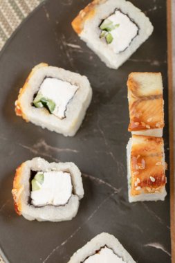 Lezzetli ejderha suşisi siyah tabakta yılan balığı ile yuvarlanıyor.