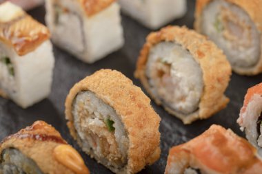 Siyah yüzeye yerleştirilmiş suşi ruloları.