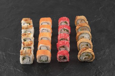 Siyah yüzeyde lezzetli taze suşi ruloları.