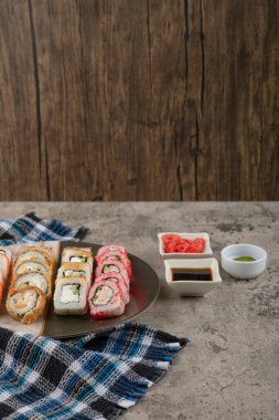 Bir tabak lezzetli suşi, soya ve wasabi ile mermer masada.