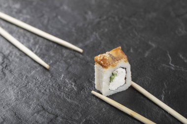 Siyah arka planda çubukları olan tek bir ejderha suşi rulosu.