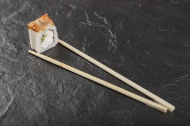 Siyah arka planda çubukları olan tek bir ejderha suşi rulosu.