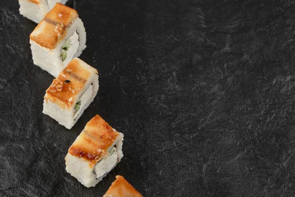Smaklig drake sushi rullar med ål på svart yta — Stockfoto