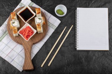 Ejderha suşisi, ahşap tahtada zencefil ve soya ile birlikte yılan balığı ile yuvarlanır.