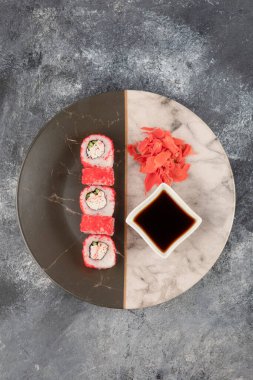 Kaliforniya suşi ruloları, zencefil ve soya sosu mermer tabakta.