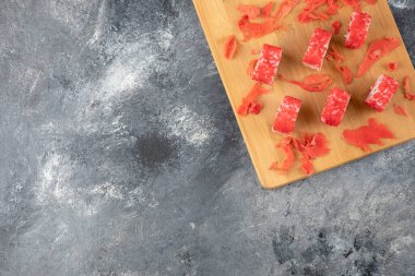 Kaliforniya suşi ruloları ve ahşap tahtaya saçılmış zencefil turşusu.