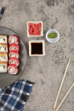 Bir tabak lezzetli suşi, soya ve wasabi ile mermer masada.