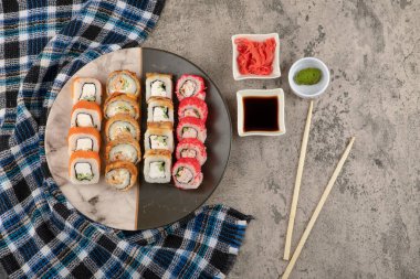 Bir tabak lezzetli suşi, soya ve wasabi ile mermer masada.
