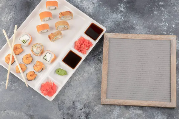 Tallrik med läckra sushi rullar och träram på marmor bakgrund — Stockfoto
