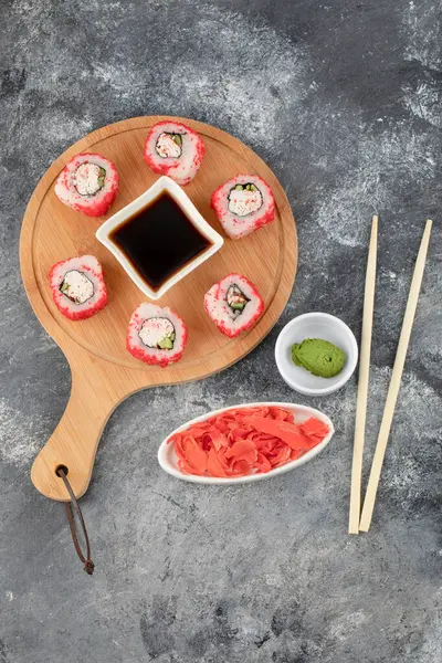 Smakrika sushirullar med röd kaviar på träskiva med sojasås — Stockfoto