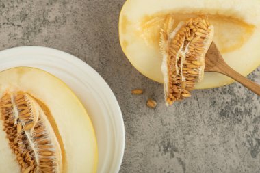 Yarısı lezzetli, beyaz tabakta, ahşap kaşıkla birlikte lezzetli bir kavun.