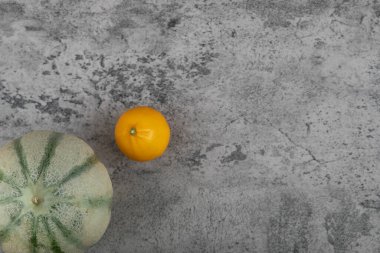 Tamamen sağlıklı portakal meyvesi ve taş masada gri balkabağı.