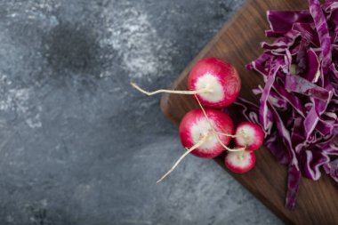 Gri arka planda tahta üzerinde doğranmış lahana ve turp.