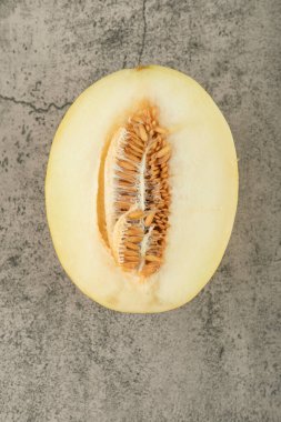 Yarım dilimlenmiş sarı kavun mermer yüzeyde