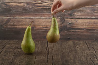 Ahşap yüzeyde taze armut tutan kadın el.