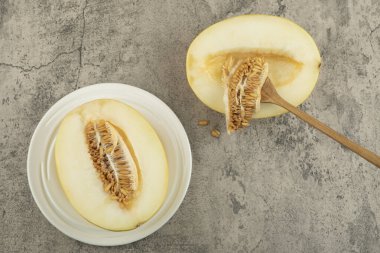 Yarısı lezzetli, beyaz tabakta, ahşap kaşıkla birlikte lezzetli bir kavun.