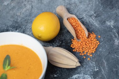 Beyaz bir kase mercimek çorbası ve ahşap bir tuvalet kağıdı.