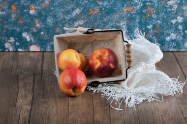 İçinde havlu olan küçük metal bir sepetin içinde elmalar.