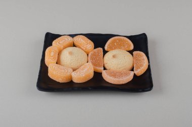 Mermer arka planda siyah bir tabakta küçük bir demet kurabiye ve marmelat. Yüksek kalite fotoğraf