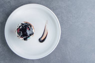 Gri arka planda lezzetli kremalı kek olan beyaz bir tabak. Yüksek kalite fotoğraf