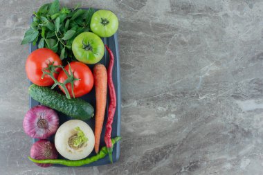 Küçük bir tabak salatalık, havuç, kırmızı ve yeşil domates, beyaz şalgam, yeşil ve kırmızı biber, kırmızı soğan ve mermer zemin üzerinde nane. Yüksek kalite fotoğraf