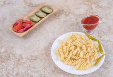 Küçük turşu tepsisi, ketçap bardağı ve mermer zemin üzerinde makarna tabağı. Yüksek kalite fotoğraf