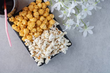 Bir bardak kolanın yanında çiçekler ve mermer arka planda bir tabak patlamış mısır. Yüksek kalite fotoğraf