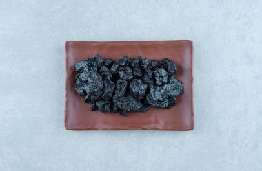 Mavi arka planda ahşap bir tabakta kurumuş ekşi kirazlar. Yüksek kalite fotoğraf