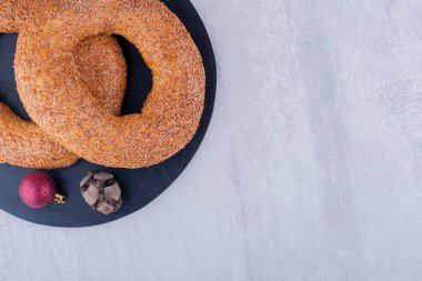 Cypress konisi, noel dekoru ve beyaz arka planda siyah tahtada susamlı simit. Yüksek kalite fotoğraf