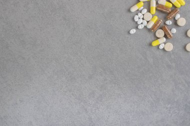 Gri arka planda çeşitli ilaç tabletleri ve kapsüller var. Yüksek kalite fotoğraf