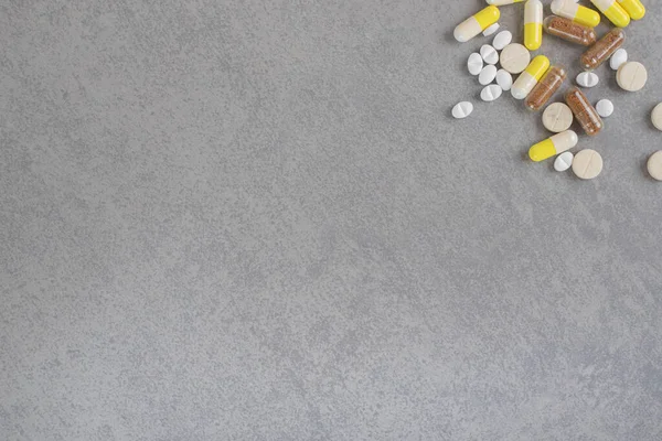 Gri arka planda çeşitli ilaç tabletleri ve kapsüller var. Yüksek kalite fotoğraf