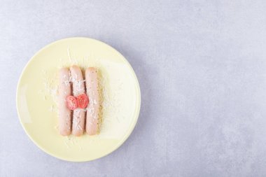 Haşlanmış sosisler domatesle süslenmiş sarı tabakta. Yüksek kalite fotoğraf