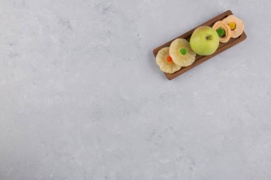 Tahtada taze yeşil elma ve kurutulmuş ananas dilimleri, kurabiyeler ve jöleler.