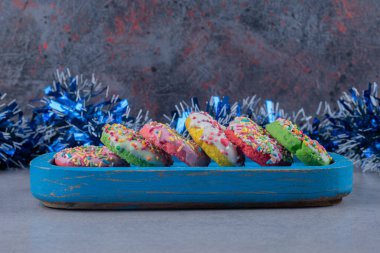 Donutlar mavi bir tepside mermer arka planda bir çelengin önünde. Yüksek kalite fotoğraf