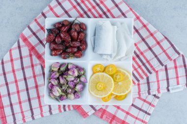 Çay poşetleri, dilimlenmiş limon, kuru gül suyu ve mermer arka planda, kasenin üzerinde çiçek. Yüksek kalite fotoğraf