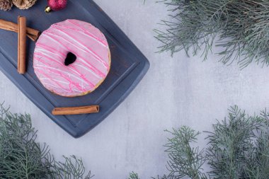 Small board with donut, cinnamon sticks, pine cones and christmas decorations on white background. High quality photo