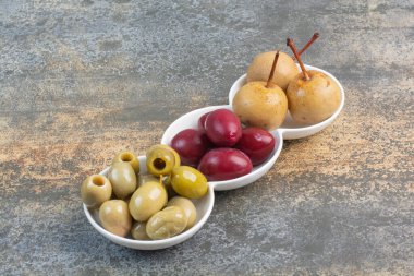 Üç tabak zeytin ve mermer arka planda lezzetli meyveler. Yüksek kalite fotoğraf