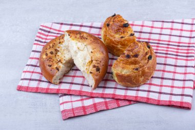 Peynirli ve masa örtüsünde kuru üzümlü yarım dilim tatlı hamur işi. Yüksek kalite fotoğraf