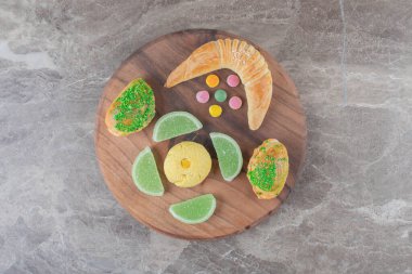 Marmelatların yanında hilal çöreği, mermer zemin üzerinde bir kurabiye ve küçük çörekler. Yüksek kalite fotoğraf