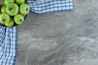 Mermer zemin üzerinde yeşil domateslerle dolu küçük bir kase. Yüksek kalite fotoğraf