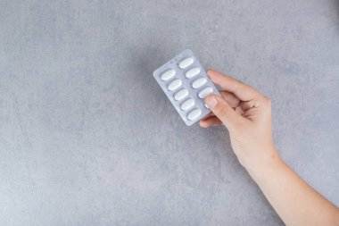 El, gri arka planda beyaz hap alıyor. Yüksek kalite fotoğraf