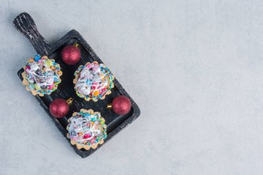 Şeker kaplı kekler ve mücevherler mermer arka planda siyah tepside. Yüksek kalite fotoğraf