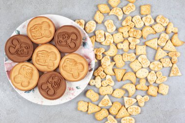 Mermer arka planda dağınık bisküvilerin yanında bir tabak kurabiye. Yüksek kalite fotoğraf