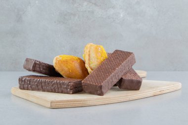 Mermer arka planda bir tahtaya sarılı çörekler ve gofretler. Yüksek kalite fotoğraf