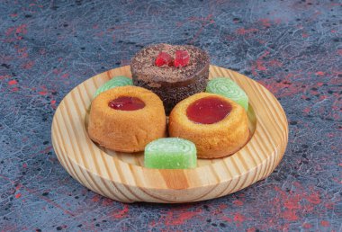 Soyut arka planda, ahşap bir tabakta çeşitli pastalar ve marmelatlar. Yüksek kalite fotoğraf