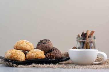 Çuval bezinde kurabiye tabağı, çay, tarçın ve kozalak. Yüksek kalite fotoğraf