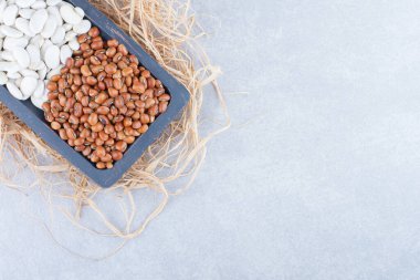 Eskimiş, ahşap bir tepsi dolusu saman, kırmızı fasulye ve mermer arka planda kuru fasulye ile doldurulmuş. Yüksek kalite fotoğraf